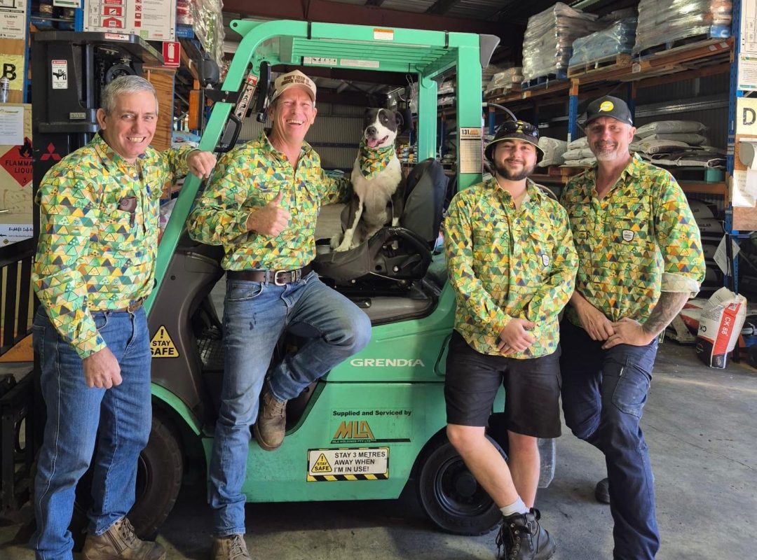 A group of farmers in TIACs shirts sitting near a forklift